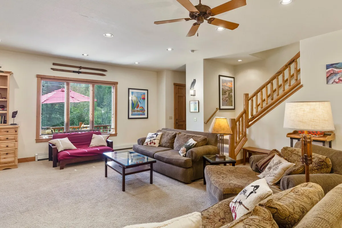 An inviting living area with a cozy sofa arrangement and a coffee table, framed by a large window that brings in natural light. The ambiance encourages relaxation, heartfelt conversations, and quiet moments.
