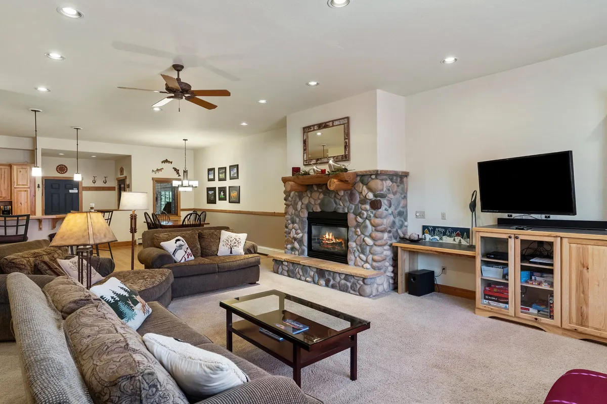 A warm and inviting living room featuring a cozy gas fireplace as its focal point, surrounded by a comfortable sofa set and a coffee table. The space is arranged for relaxation and gathering, perfect for game nights or unwinding after a day’s adventures.