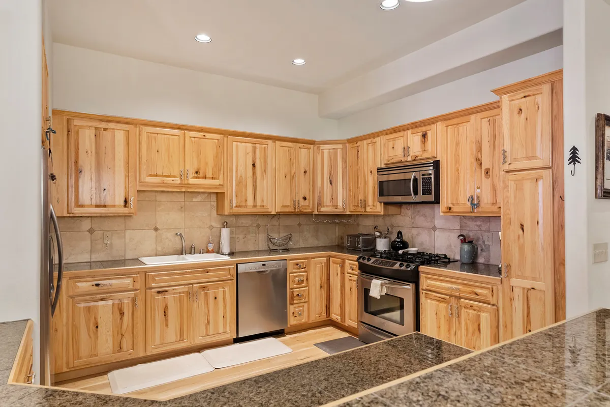 A stylish kitchen with wooden cabinets, granite countertops, and modern stainless steel appliances. The layout is open and inviting, designed for cooking, entertaining, and sharing meals with family and friends.